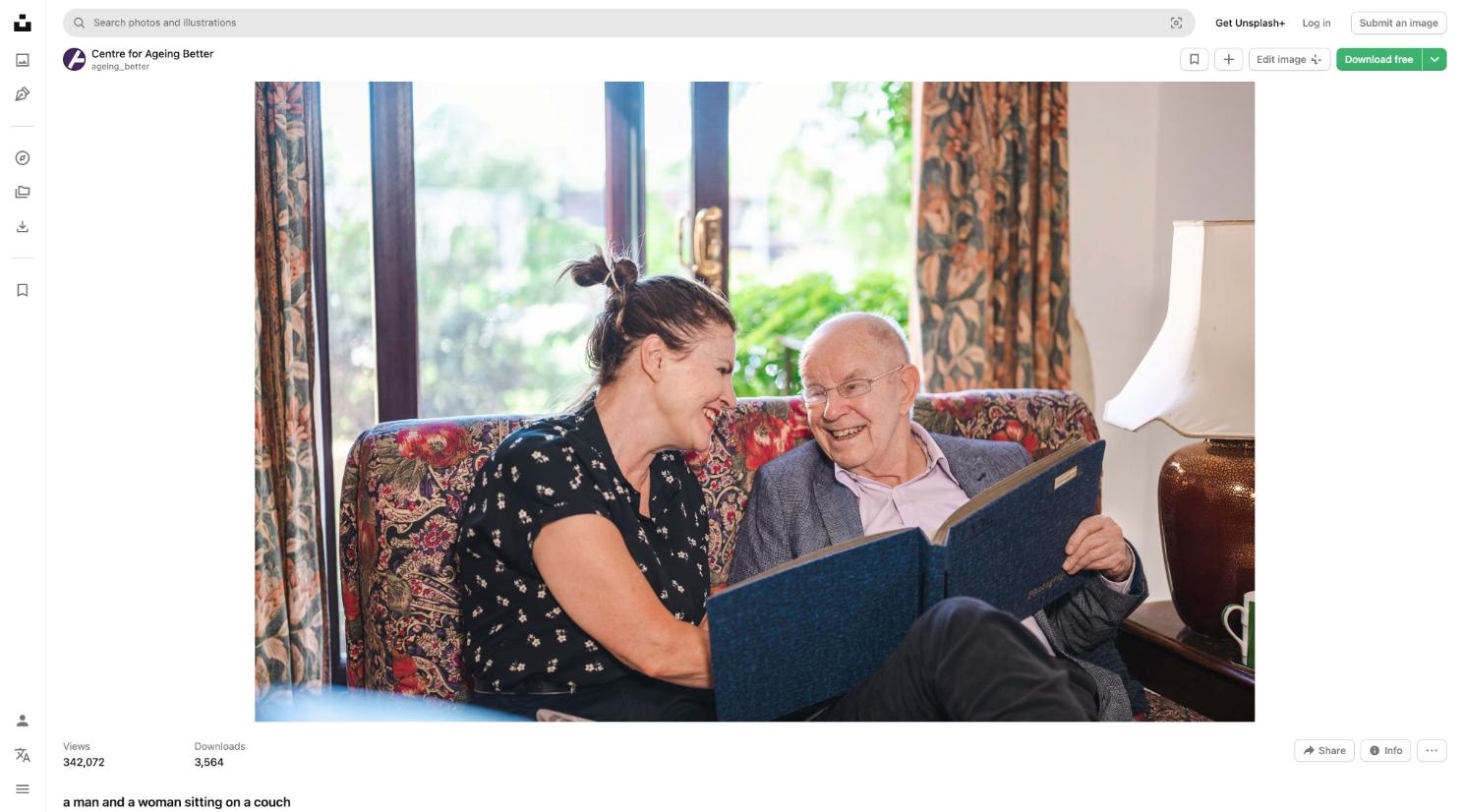Dementia Companion and elderly gentleman laughing together over a photo album at home