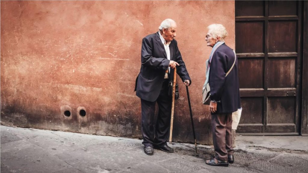 Two elderly friends having a conversation outdoors