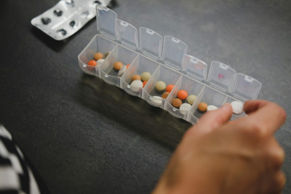 Hand picking pills from a weekly pill organizer