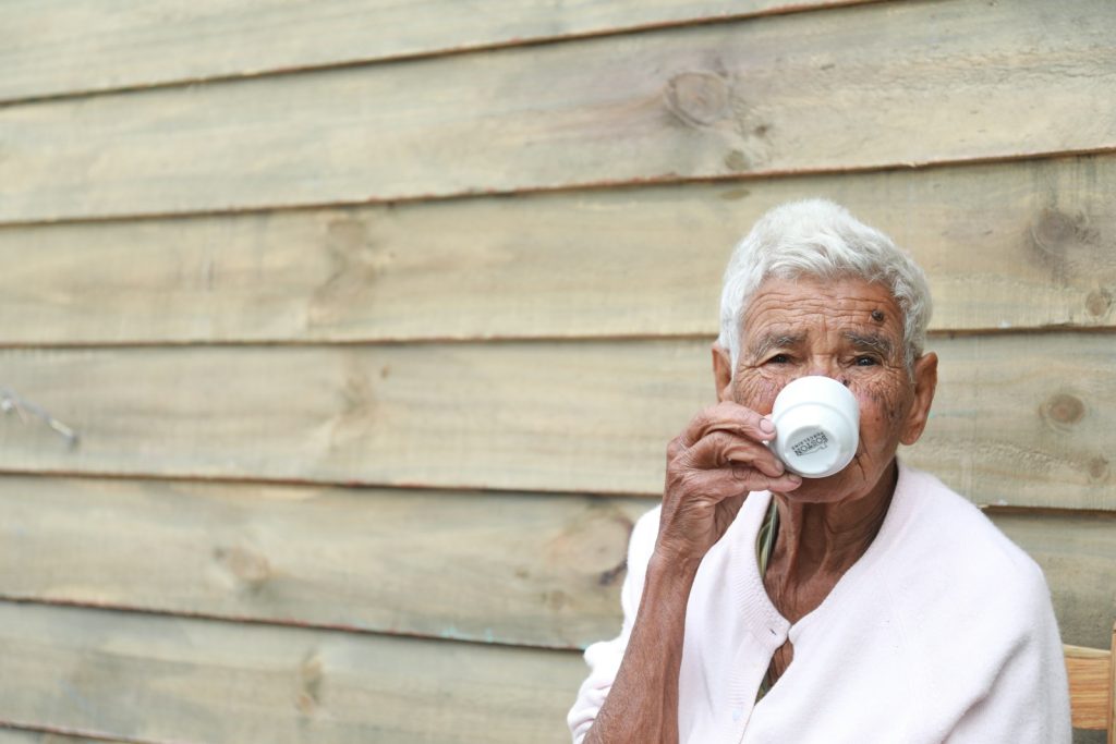 Elderly person drinking from a cup, representing mealtime and hydration care