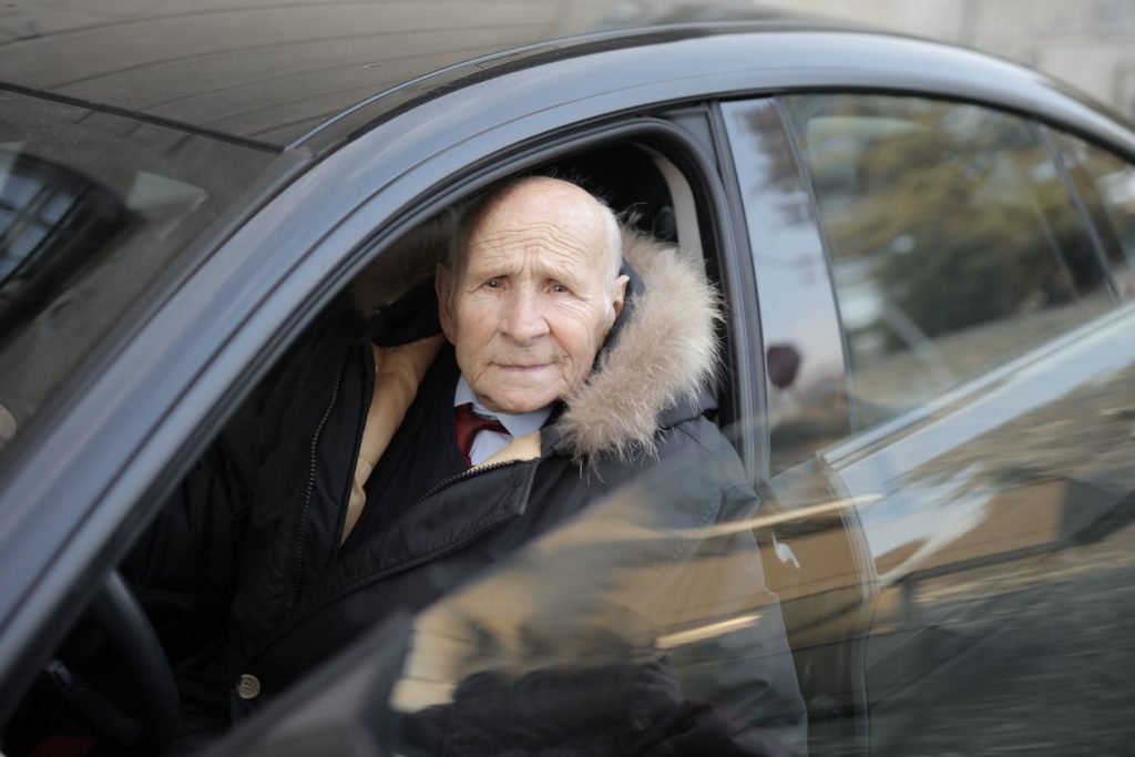 senior man driving a car, seen through the vehicle window