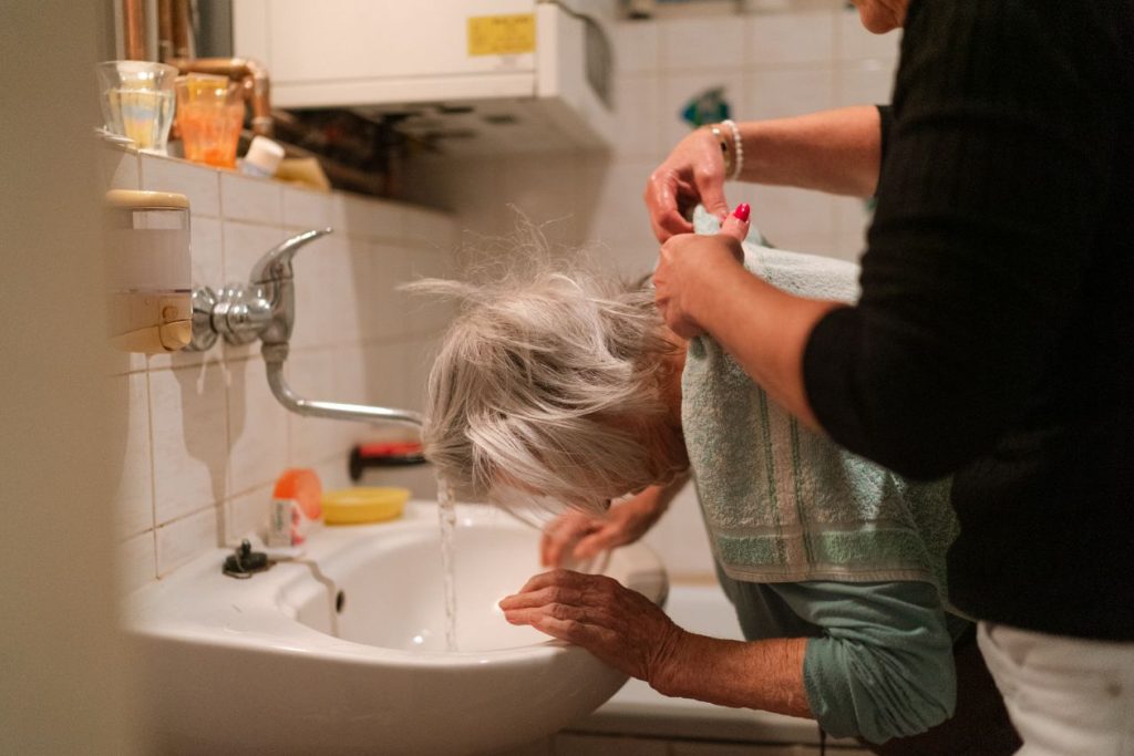 caregiver gently assisting an elderly woman with personal care