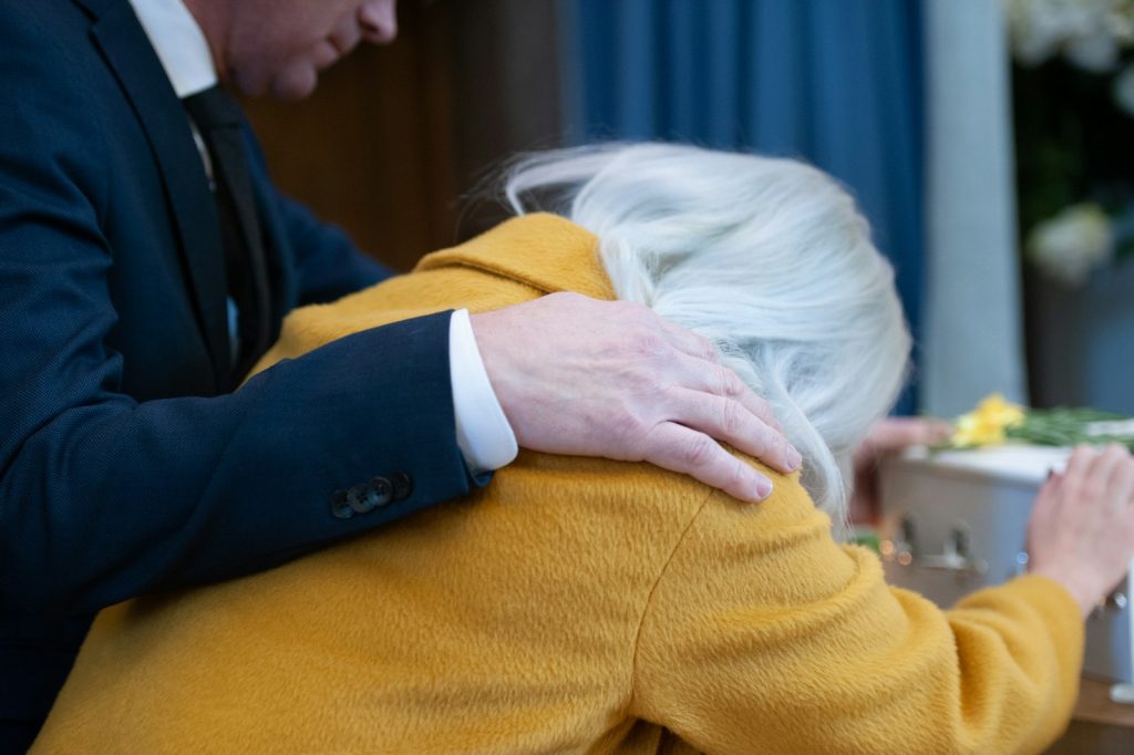 Anticipatory grief in dementia: a caregiver gently holding the hand of her older loved one