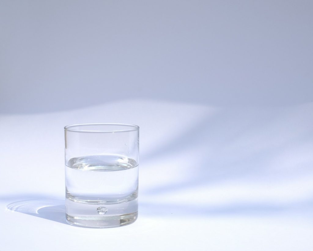 An older woman sipping water indoors to avoid dehydration and heat illness in summer