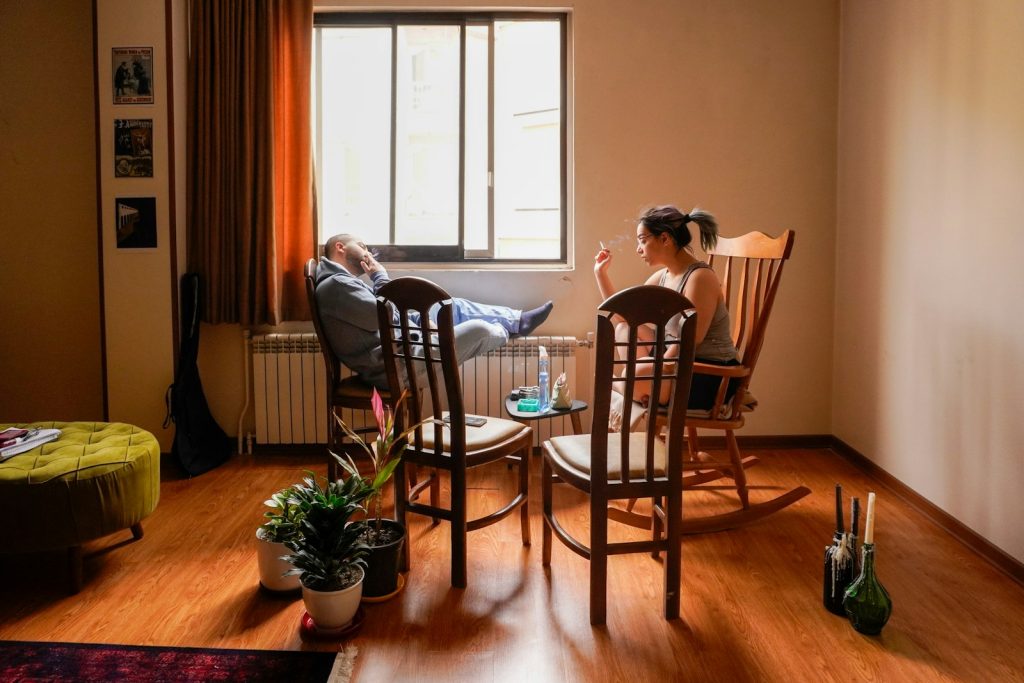 A companion offering a glass of water to an older man recovering at home, part of dementia care after hospital discharge