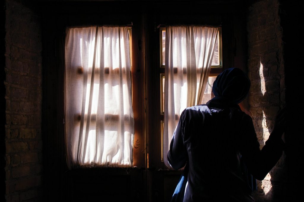 A companion checking the refrigerator and pill organizer with an older man who is living alone with dementia