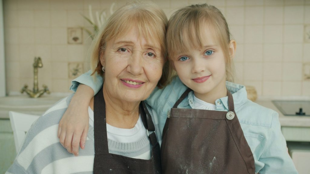 A grandmother and granddaughter smiling together in the kitchen, the family time dementia home care in Weston protects