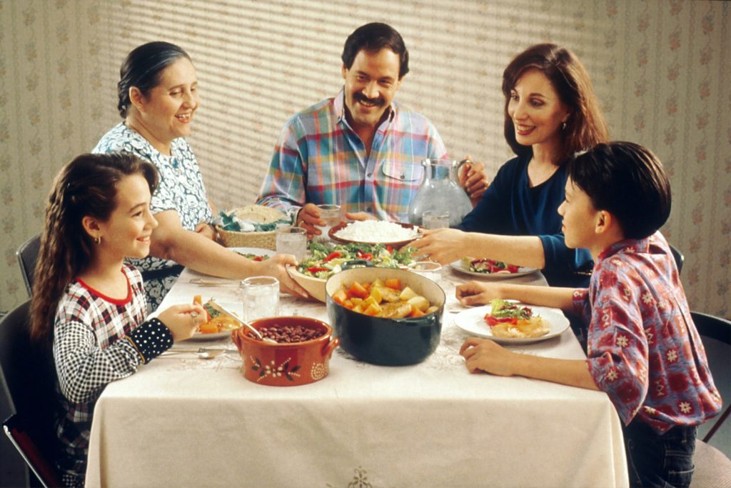 Dementia and the holidays: an older woman with dementia smiling with family at a small, calm holiday table