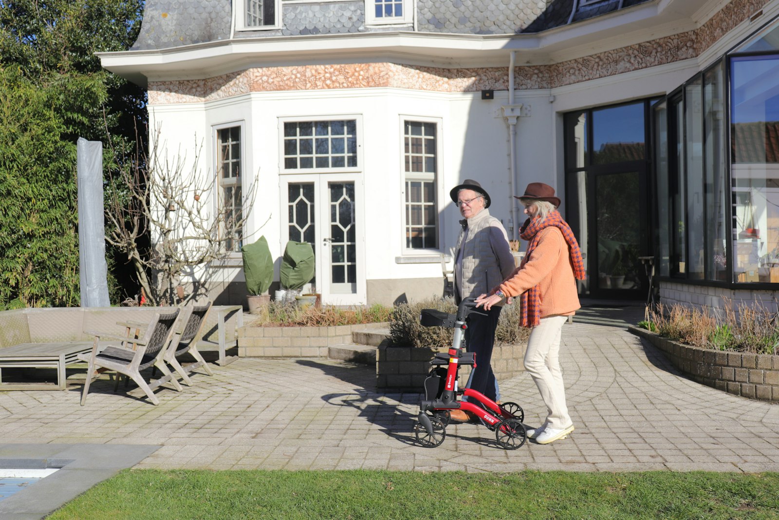 An older man with a walker out for a walk with a companion