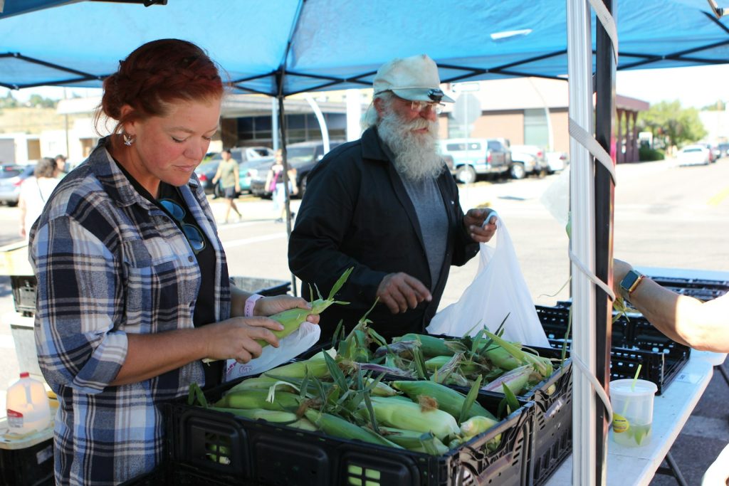 An older man and a woman choosing produce at a farmers market, a familiar errand during dementia home care in Winter Garden