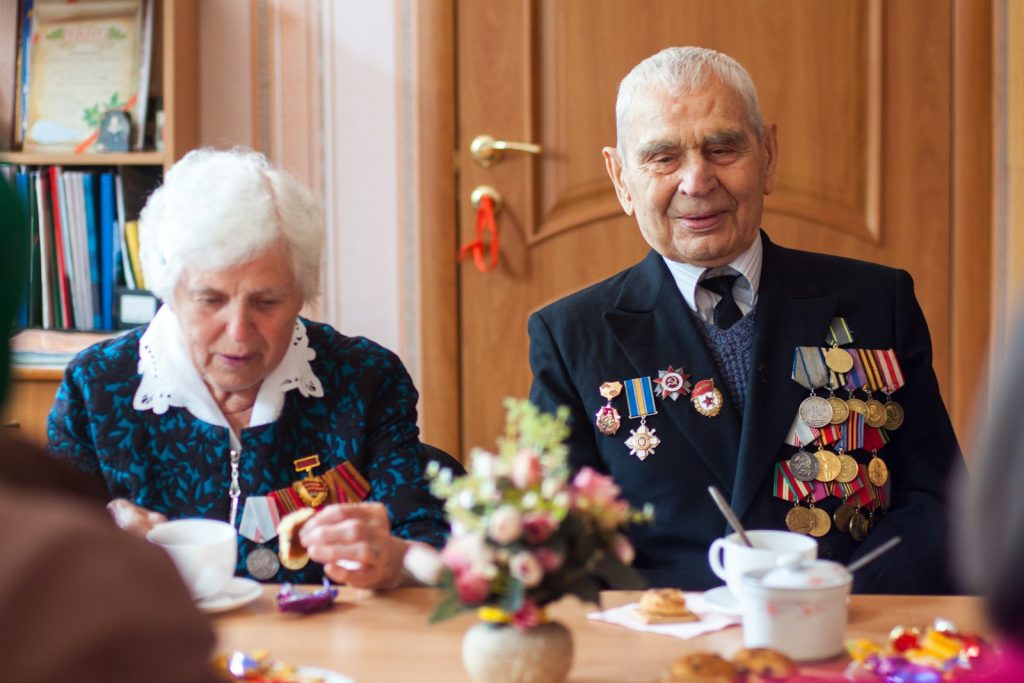 A surviving spouse sorting VA benefits paperwork and caregiver invoices for an Aid and Attendance claim