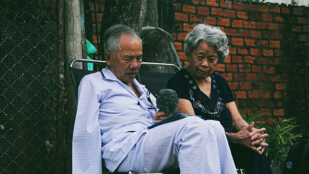 An older couple sitting side by side outdoors, a spouse caregiver getting support through dementia care in North Port