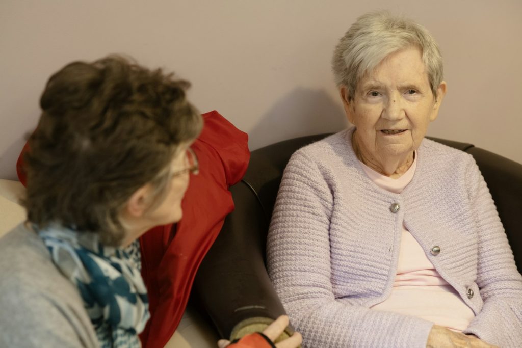 Baker Act someone with dementia: an older woman talking with a family member on the sofa