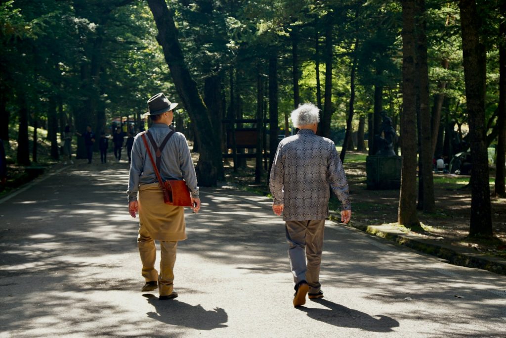 Two people walking along a shaded neighborhood path, a gentle routine for dementia care in Westchase