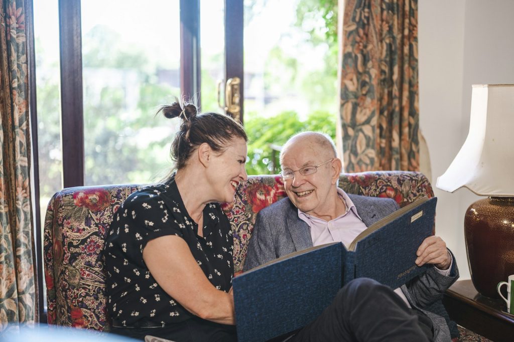 What does a dementia companion do: a companion and an older woman looking through a photo album