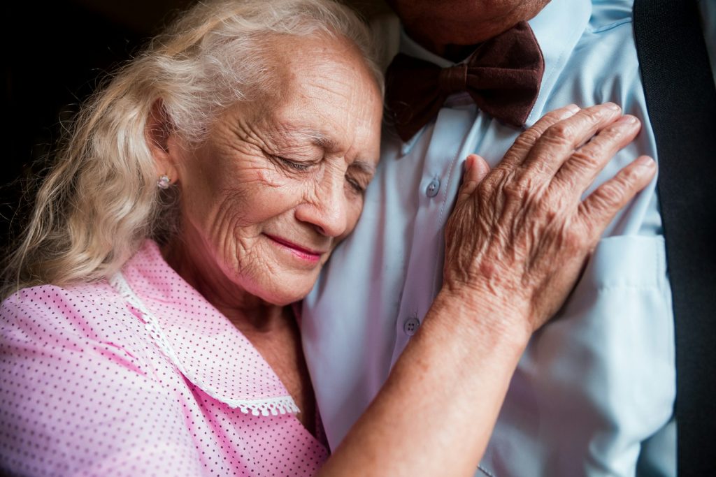 When a dementia patient refuses care: a caregiver calmly sitting beside an older woman who is hesitant about help